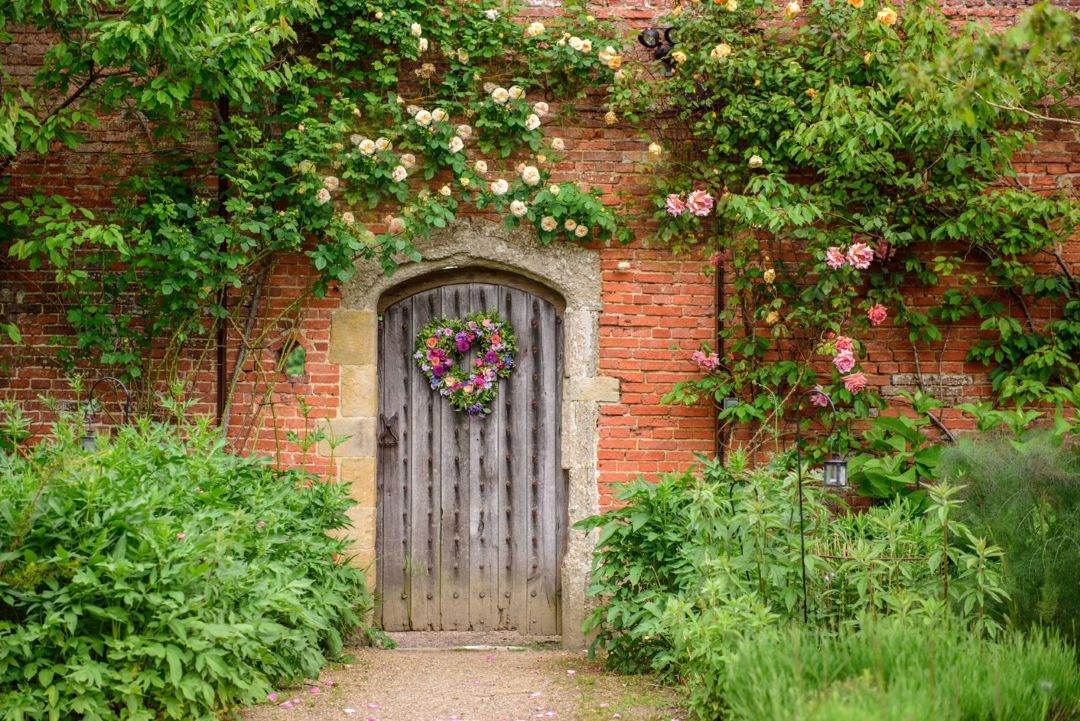 old brick building with a wooden door and flowers around it